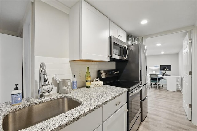 9849 Riggs St, Overland Park, KS 66212 - kitchen featuring stainless steel microwave, range with electric stovetop, a sink, white cabinetry, and light wood-type flooring