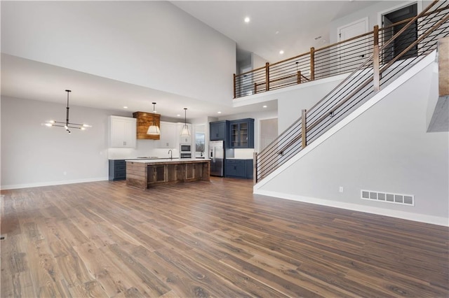 18464 Windsor St, Overland Park, KS 66085 - unfurnished living room featuring baseboards, dark wood finished floors, stairs, a sink, and a towering ceiling