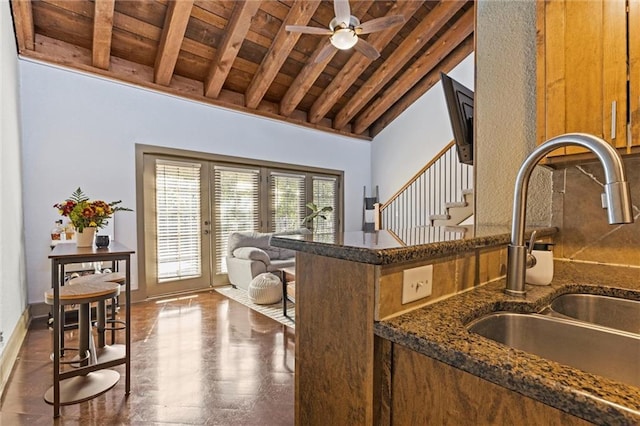 kitchen with a sink, wooden ceiling, french doors, beam ceiling, and dark stone counters