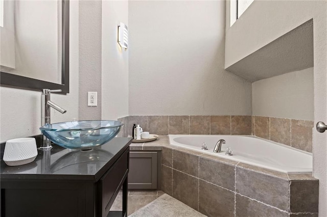 full bathroom featuring a garden tub, tile patterned floors, a textured wall, and double vanity