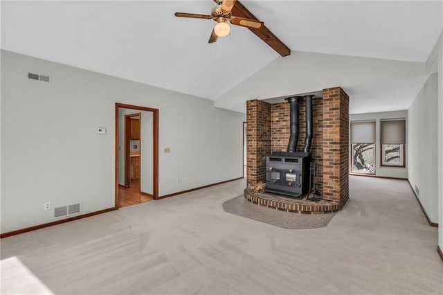unfurnished living room with carpet flooring, ceiling fan, a wood stove, and baseboards