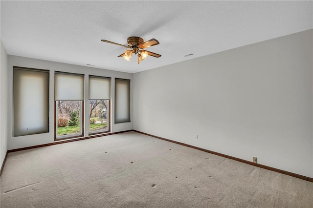 carpeted empty room with ceiling fan, baseboards, and a textured ceiling
