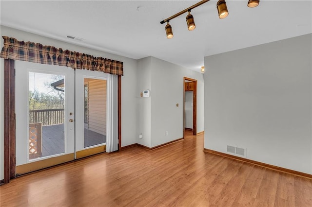 spare room with wood finished floors, french doors, and baseboards