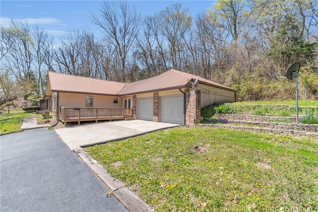 view of side of home featuring a garage, concrete driveway, metal roof, and a yard