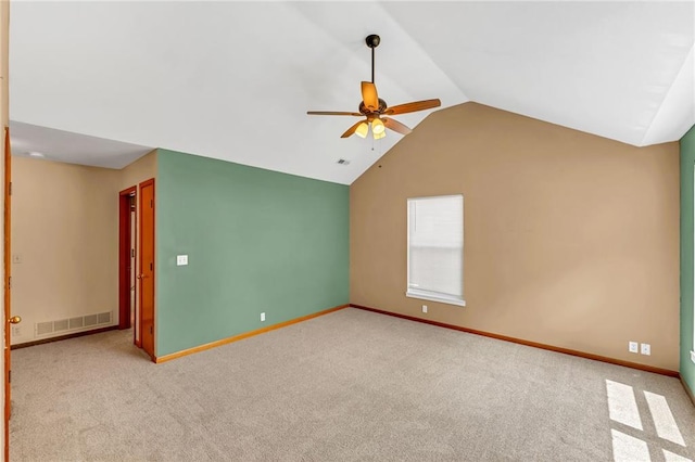 carpeted spare room with vaulted ceiling, a ceiling fan, and baseboards