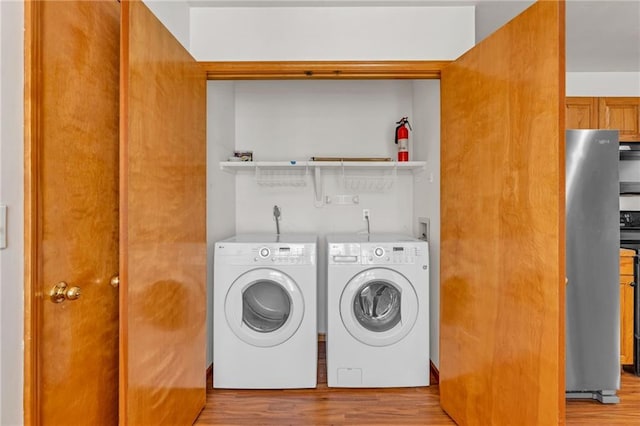 laundry area with washing machine and dryer and wood finished floors