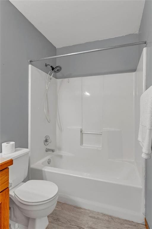 bathroom with toilet, wood finished floors, and  shower combination