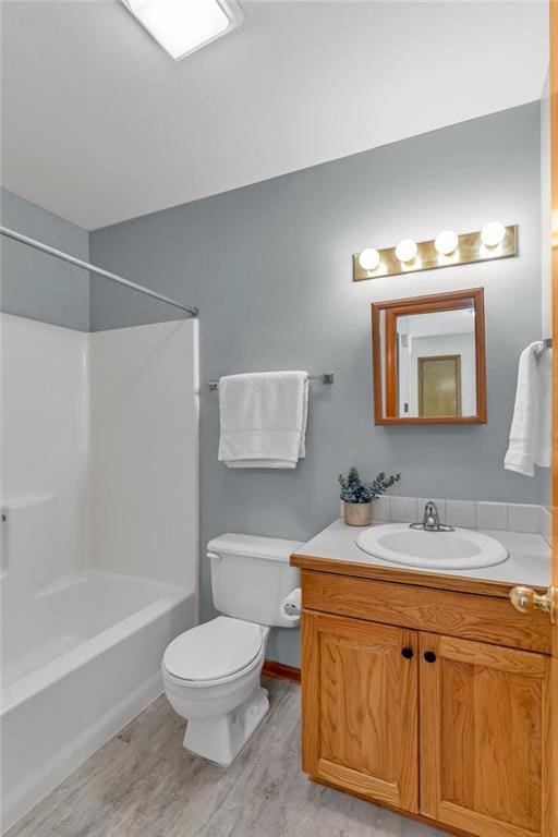 bathroom with toilet, vanity, wood finished floors, and washtub / shower combination