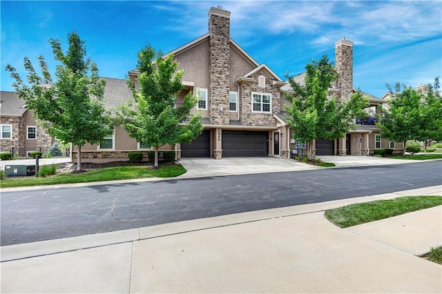15908 Fontana St Unit 240, Overland Park, KS 66085 - view of front of home with stone siding, a garage, driveway, stucco siding, and a chimney