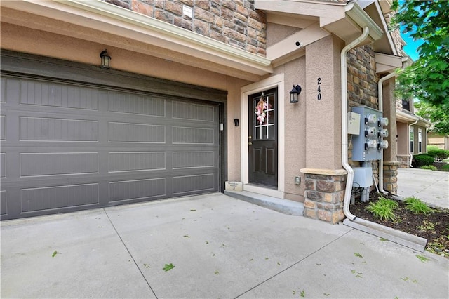 15908 Fontana St Unit 240, Overland Park, KS 66085 - doorway to property featuring stone siding, stucco siding, driveway, and a garage