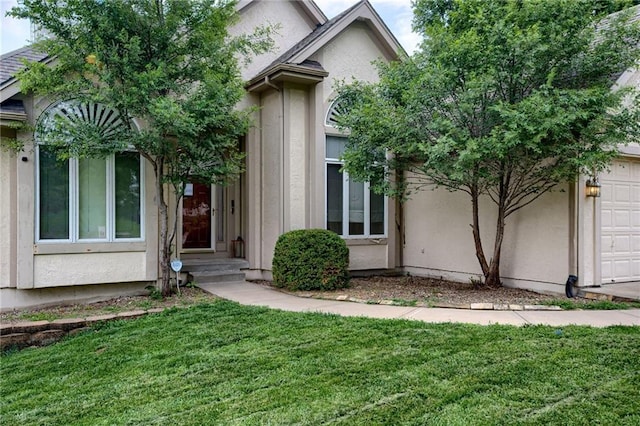 7100 N Cherry St, Gladstone, MO 64118 - doorway to property featuring an attached garage, a yard, and stucco siding