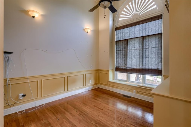 7100 N Cherry St, Gladstone, MO 64118 - spare room featuring a wainscoted wall, wood finished floors, and a ceiling fan