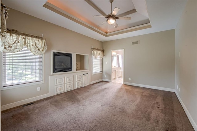 7100 N Cherry St, Gladstone, MO 64118 - unfurnished bedroom with a tray ceiling, carpet, connected bathroom, and baseboards