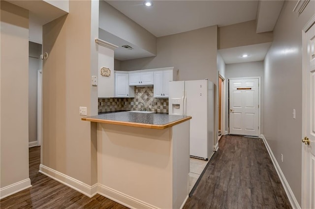 7100 N Cherry St, Gladstone, MO 64118 - kitchen featuring white refrigerator with ice dispenser, a peninsula, wood finished floors, tasteful backsplash, and white cabinets