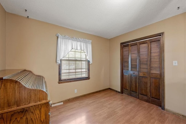 2107 N 154th Ter, Basehor, KS 66007 - unfurnished bedroom featuring light wood-style flooring, a closet, baseboards, and a textured ceiling