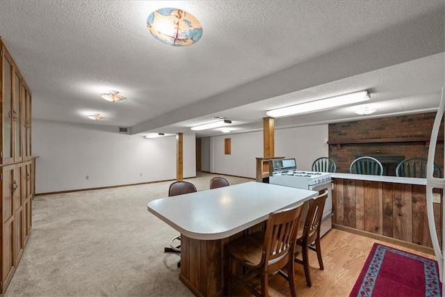 2107 N 154th Ter, Basehor, KS 66007 - kitchen with white gas stove, a textured ceiling, a breakfast bar area, baseboards, and brown cabinetry