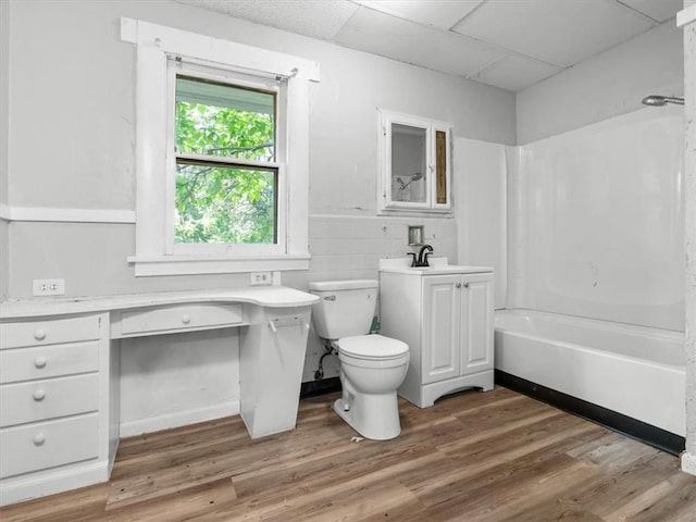 bathroom with a paneled ceiling, toilet, wood finished floors, shower / bathtub combination, and vanity