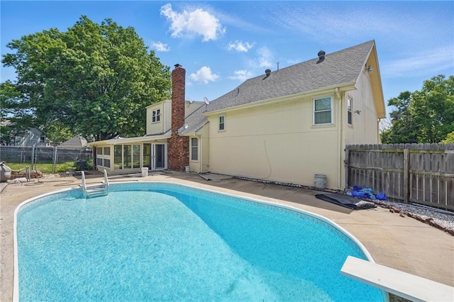 view of swimming pool featuring a fenced backyard, a diving board, a sunroom, and a patio area