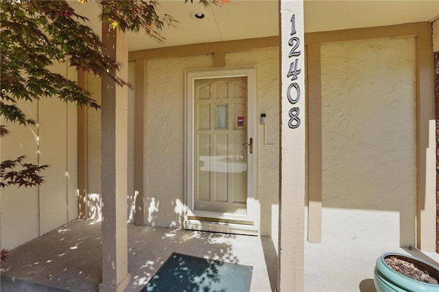 entrance to property featuring covered porch and stucco siding