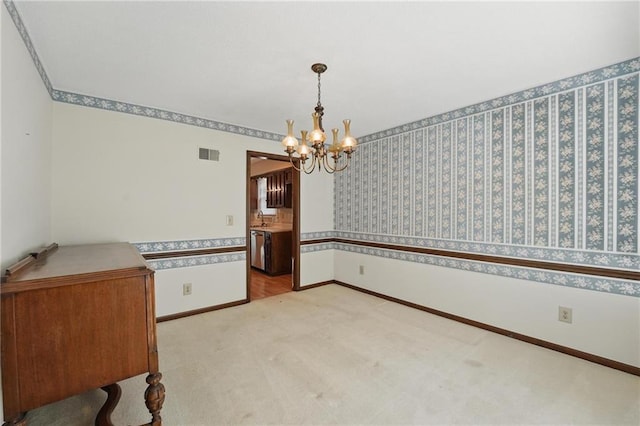 empty room featuring a chandelier, carpet flooring, baseboards, wallpapered walls, and a sink