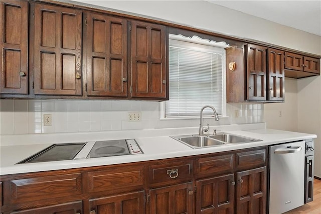 kitchen featuring a sink, stainless steel dishwasher, black electric stovetop, light countertops, and decorative backsplash