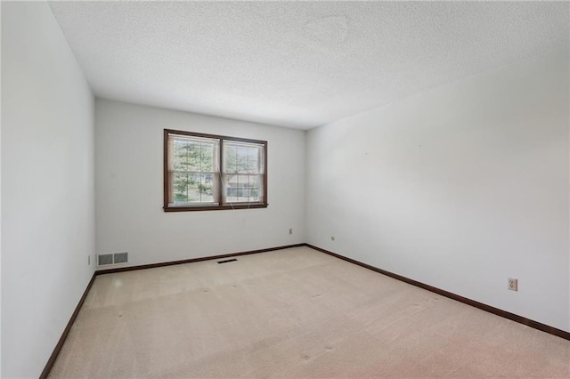 carpeted empty room with a textured ceiling and baseboards