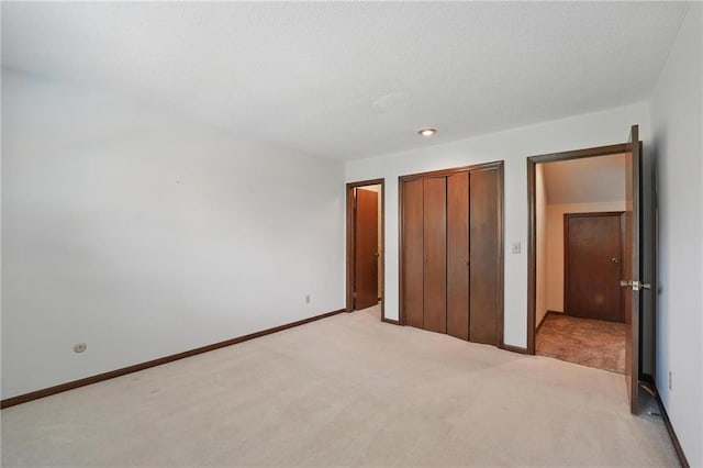 unfurnished bedroom with light colored carpet, a closet, and baseboards