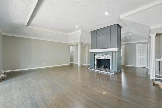 11203 Cedar St, Leawood, KS 66211 - unfurnished living room featuring ornate columns, a textured ceiling, baseboards, dark wood-style flooring, and a fireplace with raised hearth