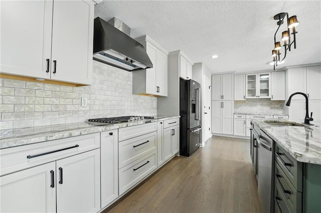 11203 Cedar St, Leawood, KS 66211 - kitchen featuring wall chimney range hood, appliances with stainless steel finishes, a sink, a textured ceiling, and dark wood-style floors