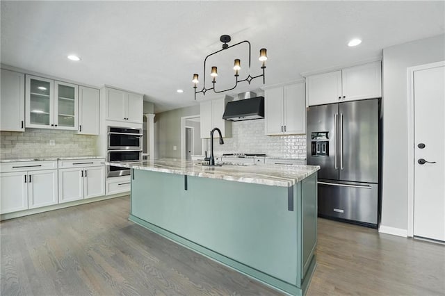 11203 Cedar St, Leawood, KS 66211 - kitchen with stainless steel appliances, wall chimney exhaust hood, backsplash, a sink, and recessed lighting