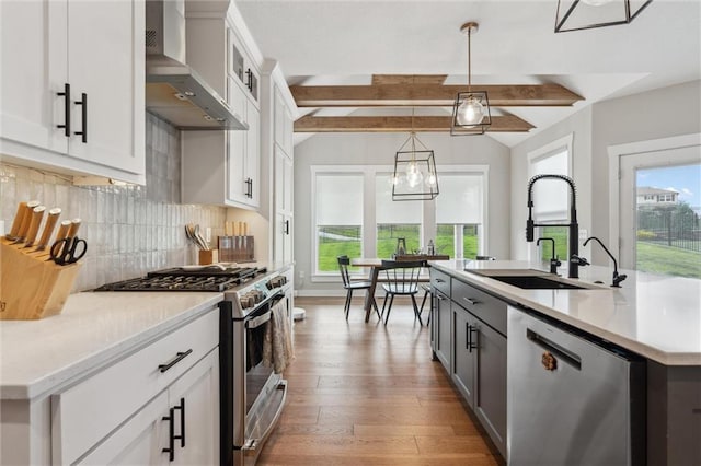 4813 NE Jamestown Dr, Lees Summit, MO 64064 - kitchen featuring stainless steel appliances, wall chimney range hood, tasteful backsplash, light countertops, and hanging light fixtures
