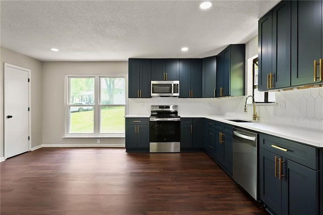 7826 Haskell Dr, Kansas City, KS 66109 - kitchen with appliances with stainless steel finishes, a sink, dark wood-style flooring, backsplash, and light countertops
