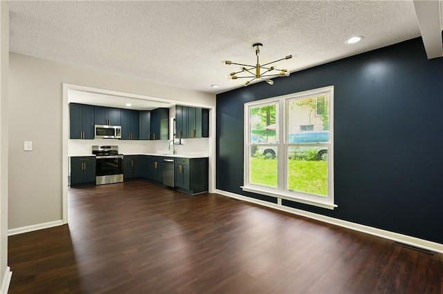 7826 Haskell Dr, Kansas City, KS 66109 - kitchen with appliances with stainless steel finishes, a chandelier, light countertops, a textured ceiling, and dark wood-style flooring