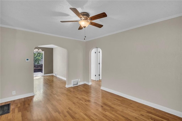 unfurnished room featuring arched walkways, light wood-style flooring, ceiling fan, baseboards, and crown molding