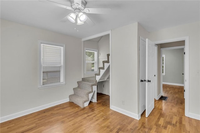 stairway with a ceiling fan, wood finished floors, and baseboards