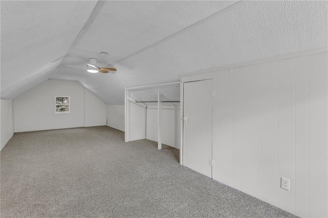 additional living space featuring carpet, a textured ceiling, vaulted ceiling, and a ceiling fan