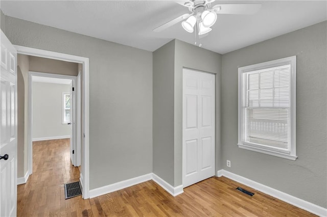 unfurnished bedroom featuring light wood-type flooring, a closet, baseboards, and a ceiling fan
