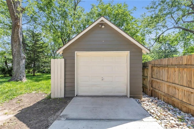 detached garage featuring fence and driveway