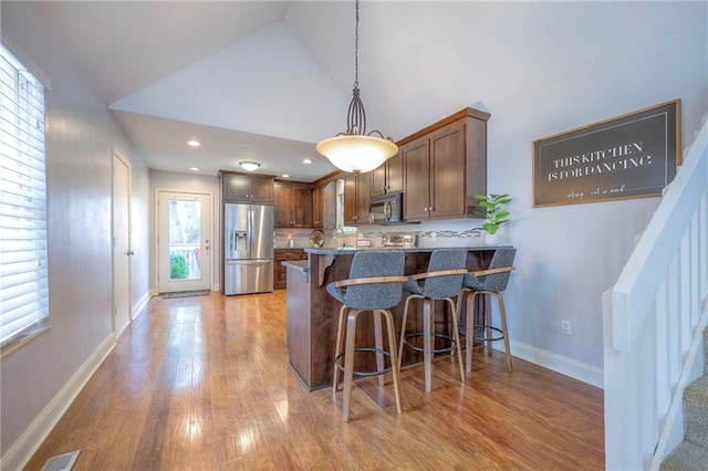 4729 Halsey St, Shawnee, KS 66216 - kitchen with stainless steel appliances, a breakfast bar area, wood finished floors, decorative light fixtures, and a peninsula