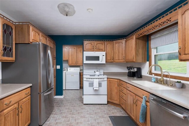 kitchen with stainless steel appliances, a sink, separate washer and dryer, light countertops, and brown cabinetry