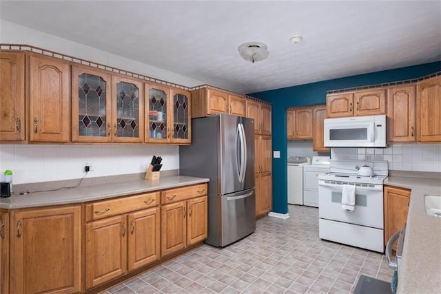 kitchen featuring white appliances, washing machine and clothes dryer, light countertops, and tasteful backsplash