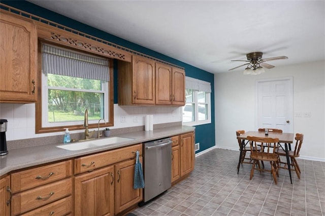 kitchen with stainless steel dishwasher, a sink, a ceiling fan, and light countertops