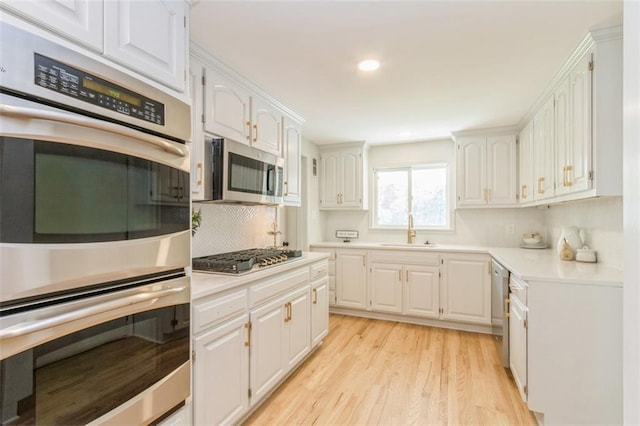 5008 W 79th St, Prairie Village, KS 66208 - kitchen featuring appliances with stainless steel finishes, a sink, light wood-type flooring, light countertops, and white cabinetry