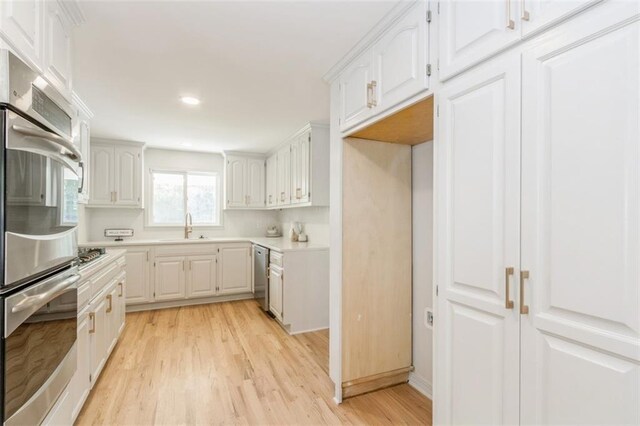 5008 W 79th St, Prairie Village, KS 66208 - kitchen with stainless steel appliances, light wood-style floors, light countertops, white cabinetry, and a sink
