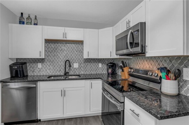 835 N 83rd Dr, Kansas City, KS 66112 - kitchen with stainless steel appliances, a sink, dark stone countertops, white cabinets, and backsplash