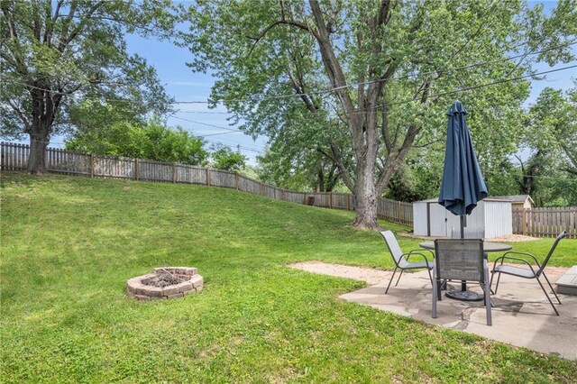 835 N 83rd Dr, Kansas City, KS 66112 - view of yard featuring a storage unit, an outdoor fire pit, a patio, and an outdoor structure