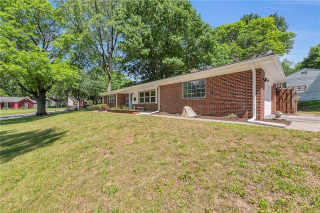 ranch-style house with brick siding, a front yard, a garage, and driveway