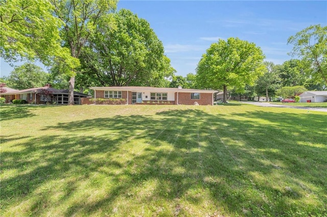 view of front facade with a front lawn, brick siding, and a chimney