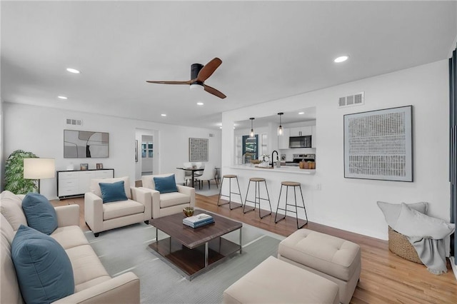 living area with wood finished floors, a ceiling fan, and recessed lighting
