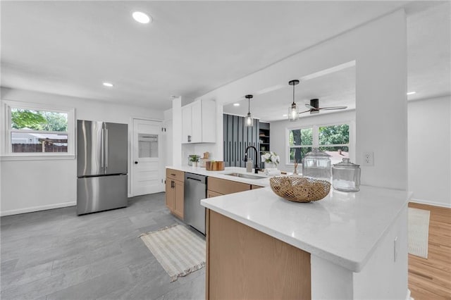 kitchen featuring appliances with stainless steel finishes, a sink, a peninsula, pendant lighting, and recessed lighting